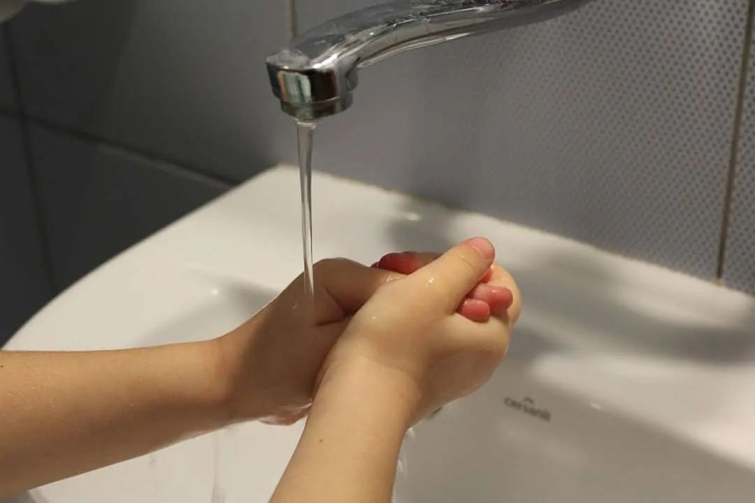 washing hands under faucet